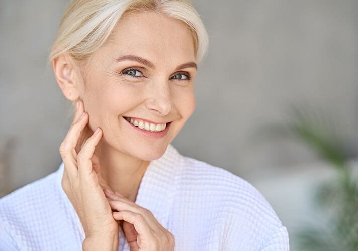 Older woman looking at her facial features and smiling