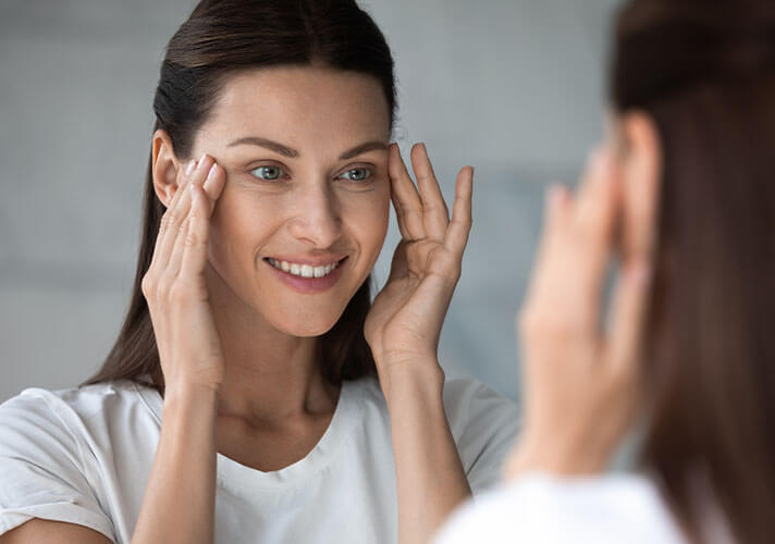 Woman looking at her eyes in a mirror