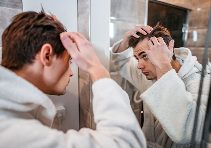 Man looking over his hair progress in a mirror